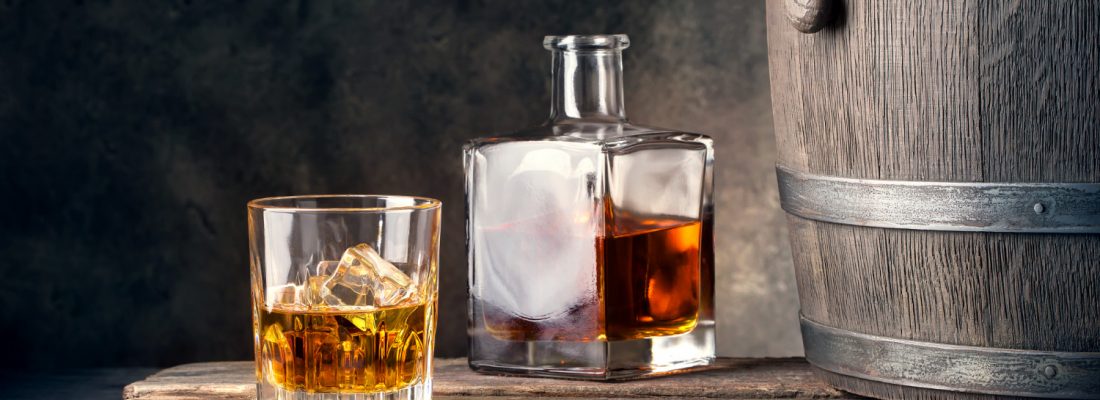 glass-of-whiskey-with-ice-decanter-and-barrel